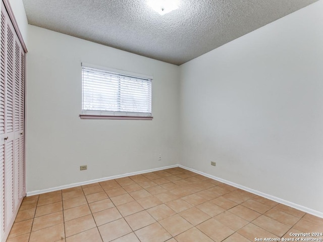 interior space featuring a closet, light tile patterned flooring, and a textured ceiling