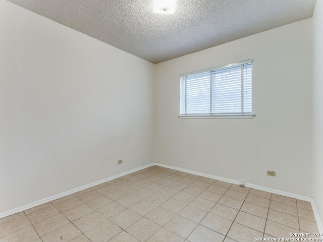 spare room featuring light tile patterned flooring and a textured ceiling