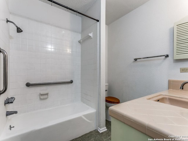 full bathroom with vanity, tile patterned floors, tiled shower / bath combo, toilet, and a textured ceiling