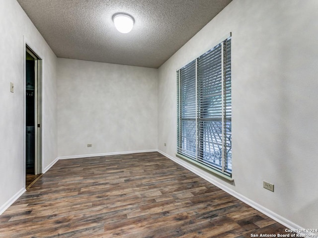 unfurnished room with a textured ceiling and dark hardwood / wood-style floors