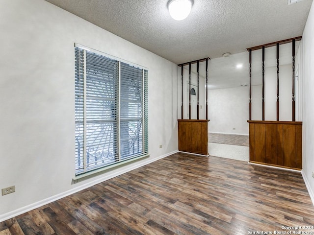 spare room with a textured ceiling and dark wood-type flooring