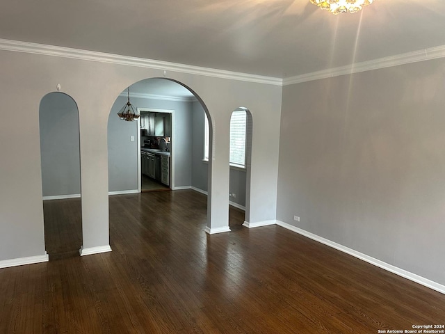 spare room with dark hardwood / wood-style floors, ornamental molding, and an inviting chandelier