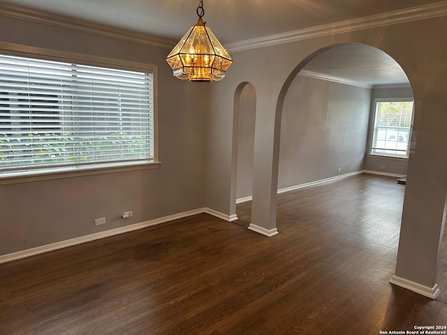 empty room with dark wood-type flooring, a notable chandelier, and ornamental molding