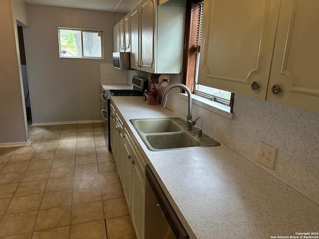 kitchen featuring decorative backsplash, appliances with stainless steel finishes, light tile patterned floors, and sink