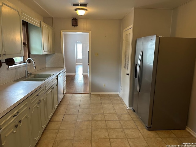 kitchen featuring appliances with stainless steel finishes, light wood-type flooring, tasteful backsplash, and sink