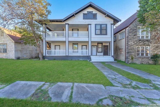 view of front of home featuring a porch, a balcony, and a front lawn