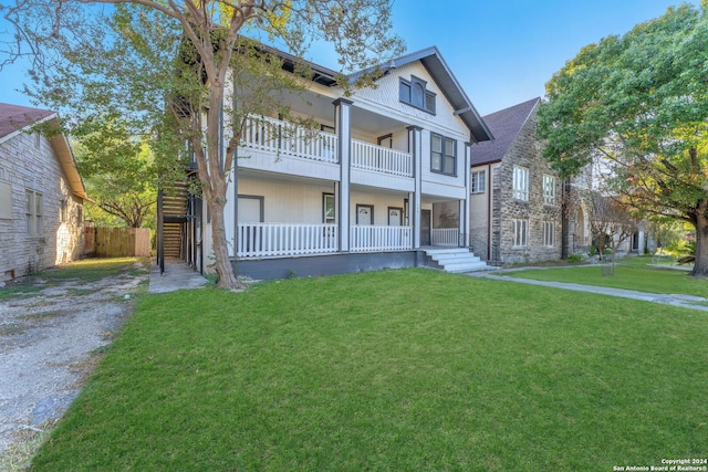 view of front of property featuring a balcony and a front lawn