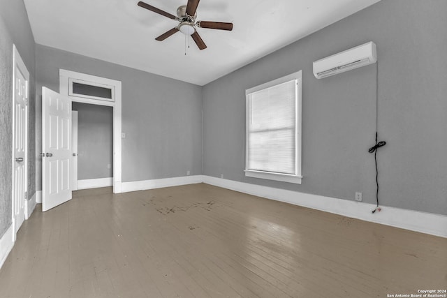 empty room featuring a wall mounted air conditioner, ceiling fan, and wood-type flooring