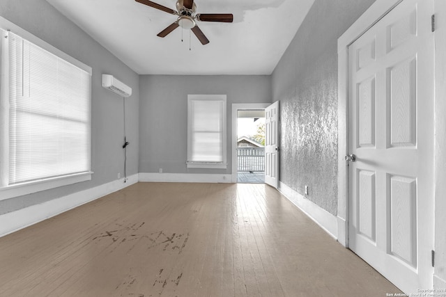 empty room with hardwood / wood-style flooring, ceiling fan, and a wall mounted air conditioner