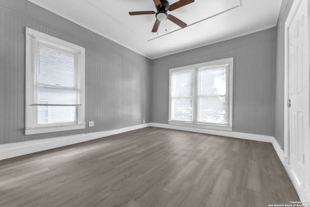 empty room featuring ceiling fan, a healthy amount of sunlight, and hardwood / wood-style flooring