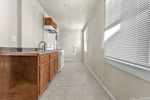 kitchen with light tile patterned flooring, white range oven, and sink