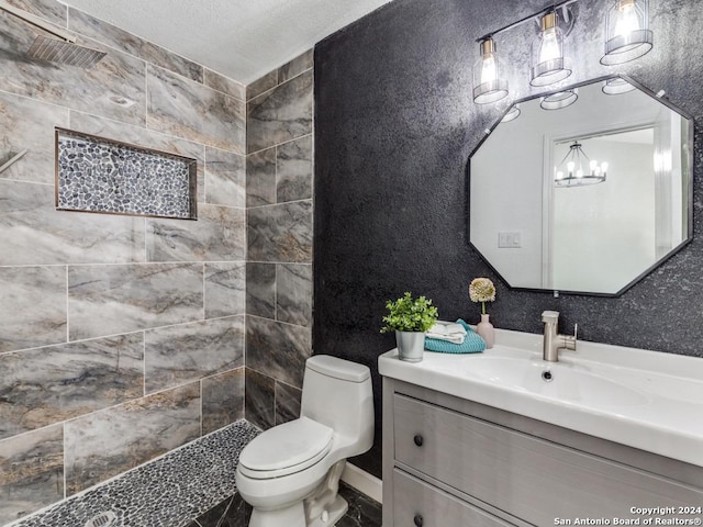 bathroom featuring a tile shower, a chandelier, a textured ceiling, toilet, and vanity