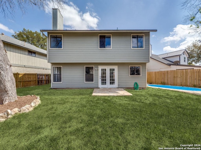 rear view of house featuring a lawn, a patio area, and french doors