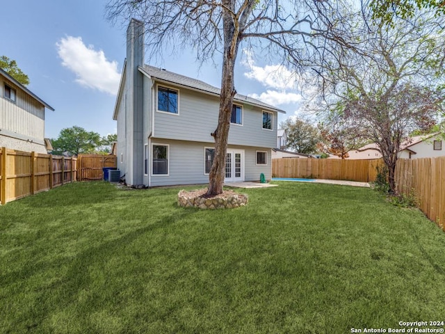 rear view of house featuring central AC unit, a patio area, a yard, and french doors