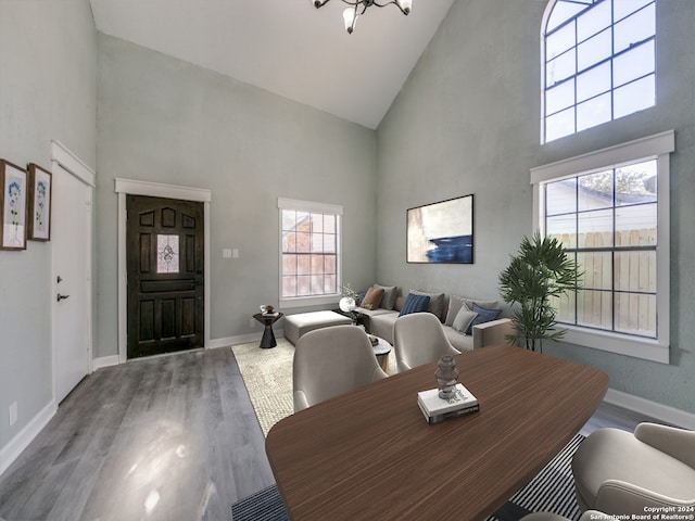 dining room with plenty of natural light, wood-type flooring, high vaulted ceiling, and a chandelier