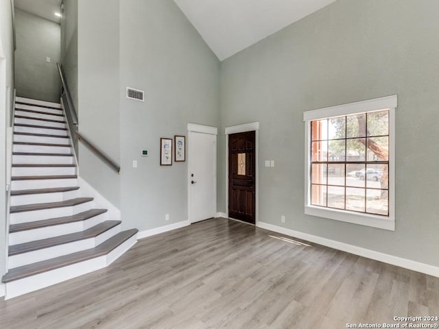 foyer with high vaulted ceiling and light hardwood / wood-style flooring