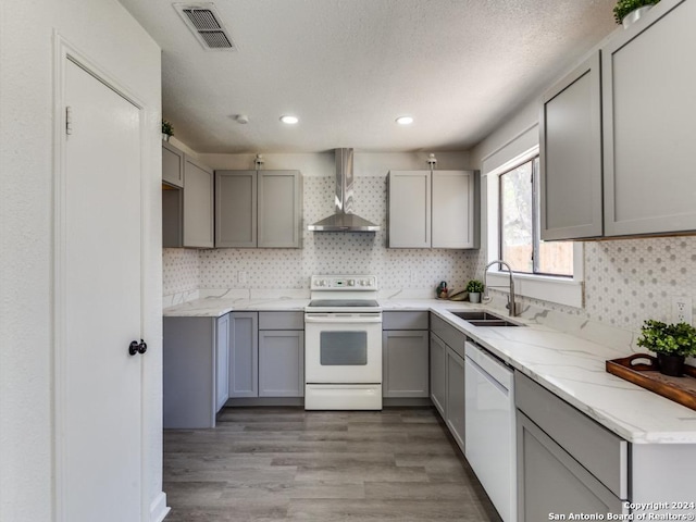 kitchen with gray cabinetry, sink, wall chimney exhaust hood, and white appliances