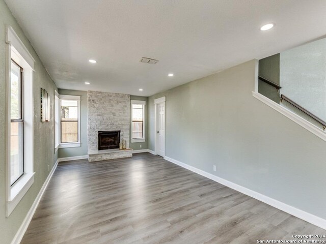 unfurnished living room featuring a stone fireplace and light wood-type flooring