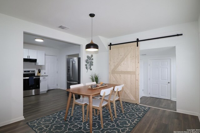 dining space with a barn door and dark hardwood / wood-style flooring