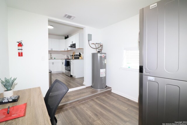 interior space with electric water heater, dark wood-type flooring, and stacked washer / drying machine