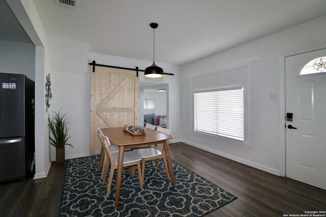 dining room featuring a barn door and dark hardwood / wood-style floors