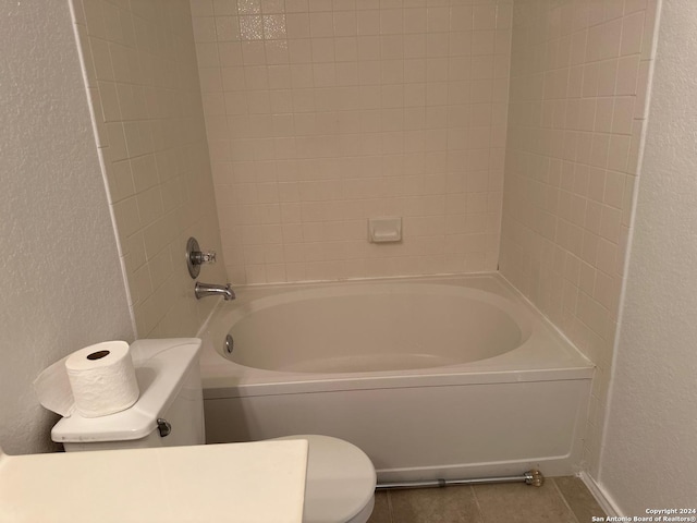 bathroom featuring tile patterned floors, toilet, and tiled shower / bath