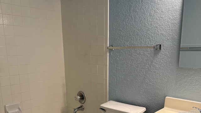 bathroom featuring tiled shower / bath and toilet