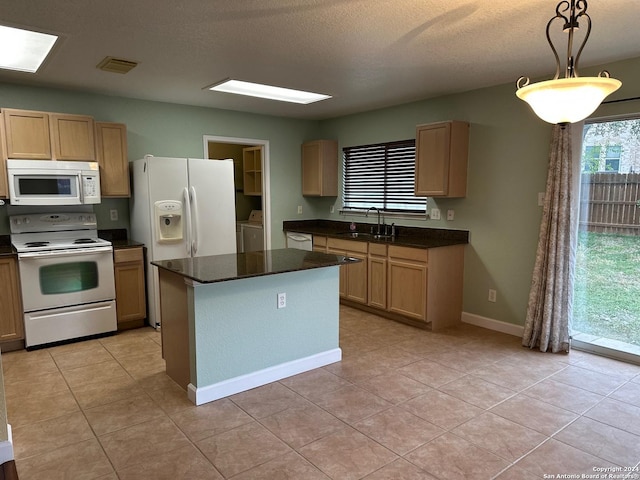 kitchen featuring white appliances, sink, independent washer and dryer, decorative light fixtures, and light tile patterned flooring