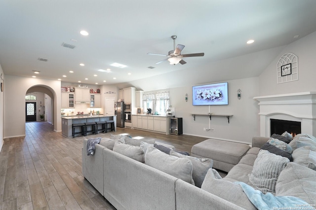 living room featuring lofted ceiling, ceiling fan, wood-type flooring, and a wealth of natural light