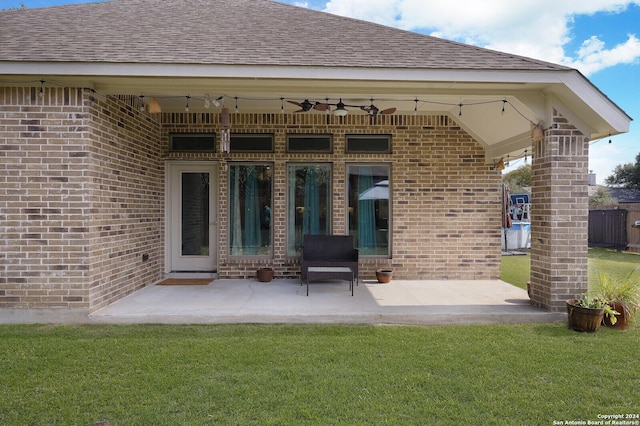 back of property with ceiling fan, a yard, and a patio