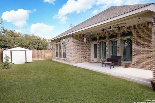 back of house featuring a lawn, a patio area, and a shed