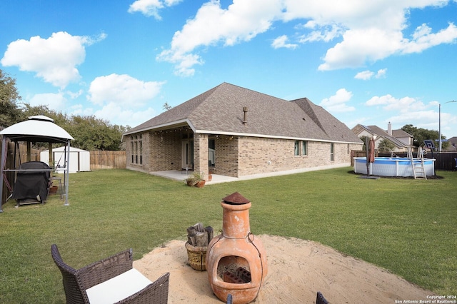 exterior space featuring a shed, a fenced in pool, a patio area, a fireplace, and a gazebo