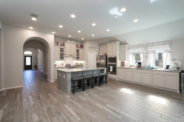 kitchen with a breakfast bar area, a large island with sink, light hardwood / wood-style flooring, and stainless steel appliances