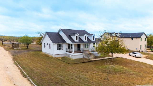 cape cod house featuring covered porch and a front yard