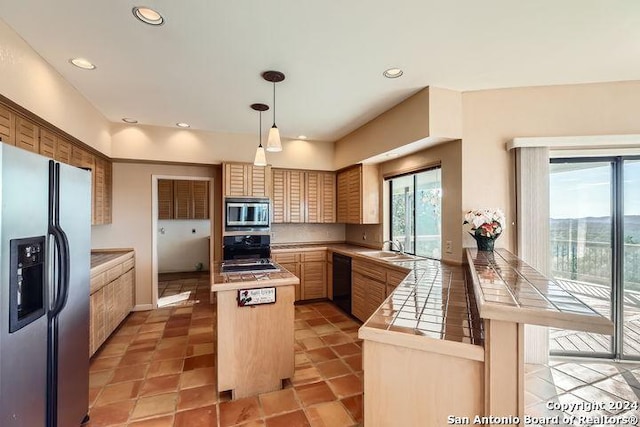 kitchen with black appliances, sink, decorative light fixtures, tile counters, and kitchen peninsula