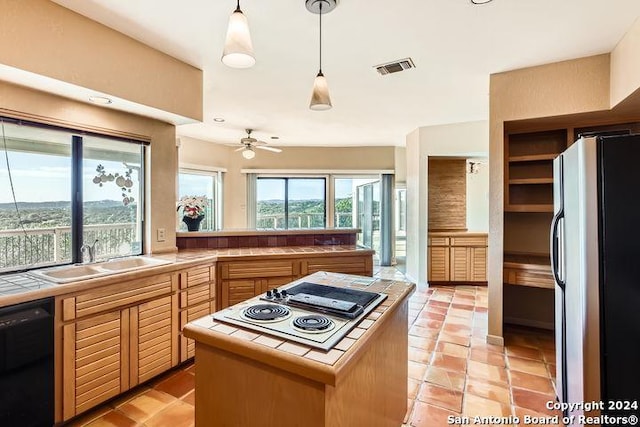 kitchen featuring stainless steel fridge, tile counters, and plenty of natural light