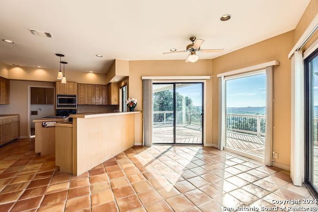 kitchen with hanging light fixtures, ceiling fan, light tile patterned floors, appliances with stainless steel finishes, and kitchen peninsula