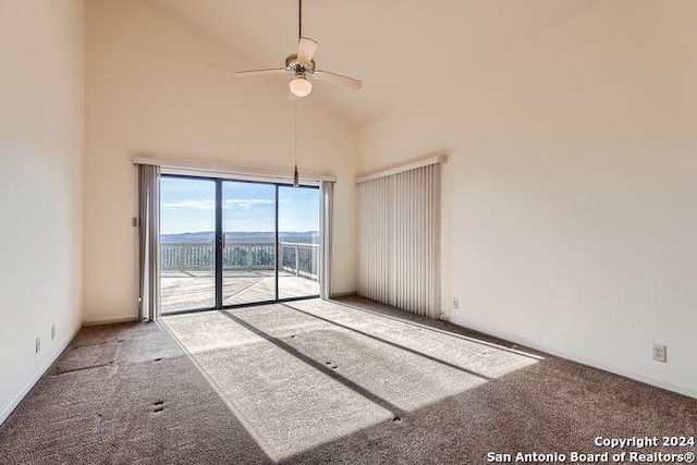 carpeted empty room with ceiling fan and high vaulted ceiling