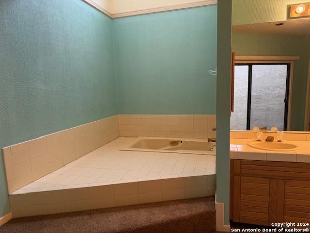 bathroom with tiled tub and vanity