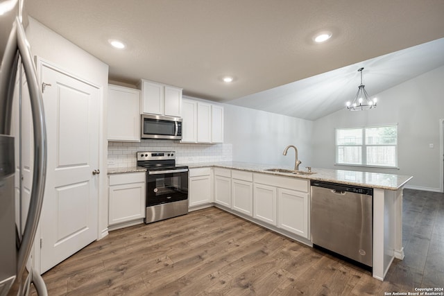 kitchen with kitchen peninsula, sink, dark hardwood / wood-style floors, appliances with stainless steel finishes, and white cabinetry