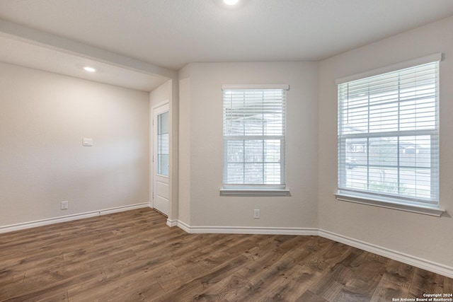 spare room with a healthy amount of sunlight and dark wood-type flooring