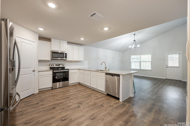 kitchen with lofted ceiling, decorative light fixtures, white cabinetry, and appliances with stainless steel finishes