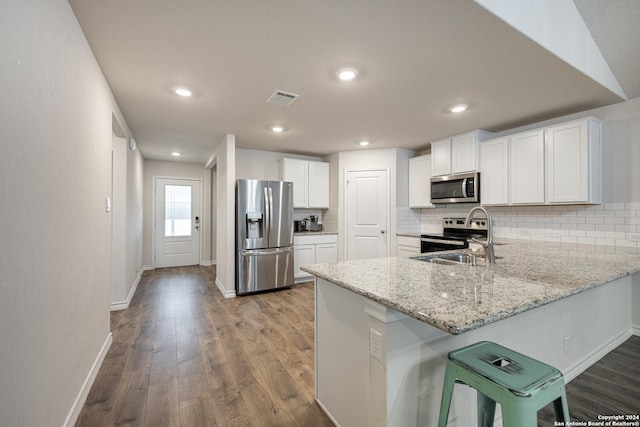 kitchen featuring backsplash, sink, hardwood / wood-style flooring, appliances with stainless steel finishes, and white cabinetry