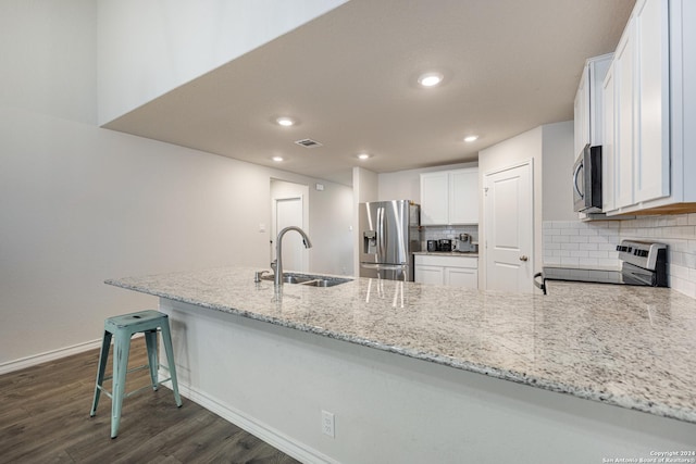 kitchen with sink, dark hardwood / wood-style flooring, kitchen peninsula, white cabinets, and appliances with stainless steel finishes