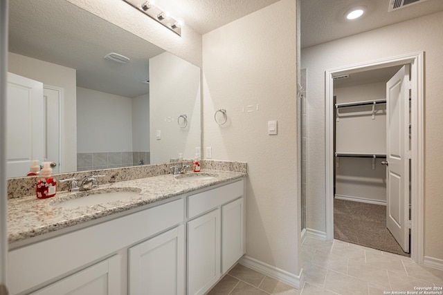 bathroom with tile patterned floors, vanity, a shower with shower door, and a textured ceiling