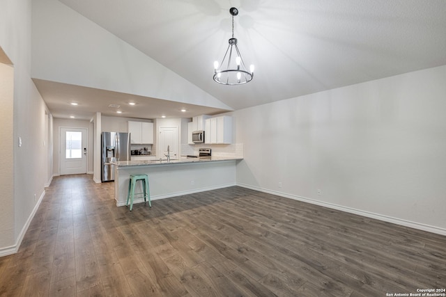 kitchen with white cabinetry, dark hardwood / wood-style floors, a notable chandelier, kitchen peninsula, and appliances with stainless steel finishes