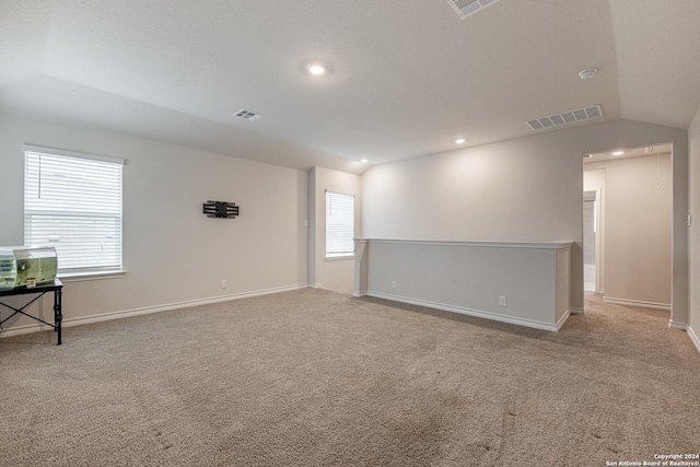 spare room with light colored carpet and vaulted ceiling