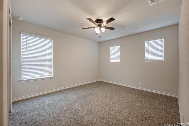 carpeted spare room with ceiling fan and a textured ceiling