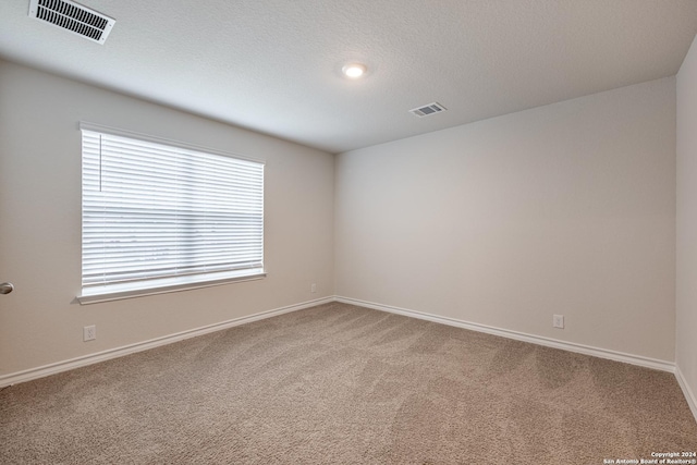 carpeted empty room with a textured ceiling