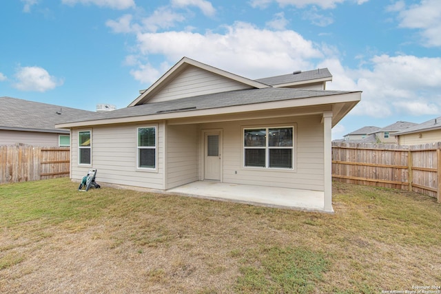 back of property with a yard and a patio